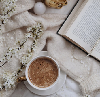 Livre ouvert et tasse café sur plaid crème  
