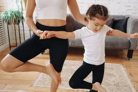 Un adulte dont on ne voit pas la tête fait du yoga avec un enfant