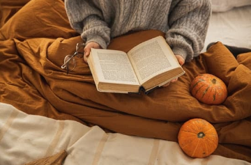 Mains tenant un livre ouvert sur un édredon