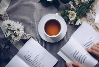 une tasse de café, des livres ouverts et des fleurs sur une nappe